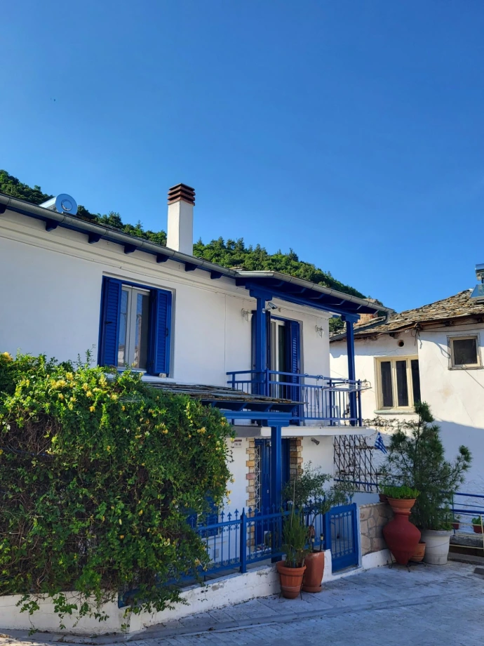 a white house with blue shutters and a balcony